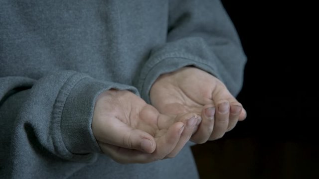 Child's hands begging. The dirty hands of a homeless child beg for alms.