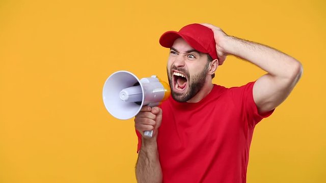 Fun crazy delivery man in red cap blank t-shirt workwear scream in megaphone announces discounts sale Hurry up isolated on yellow background studio Professional male employee courier Service concept