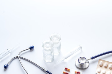 Flu treatment - pills and stethoscope on white table copy space
