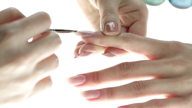 Application of nail polish on nails. Woman applying nude nail polish. manicure process