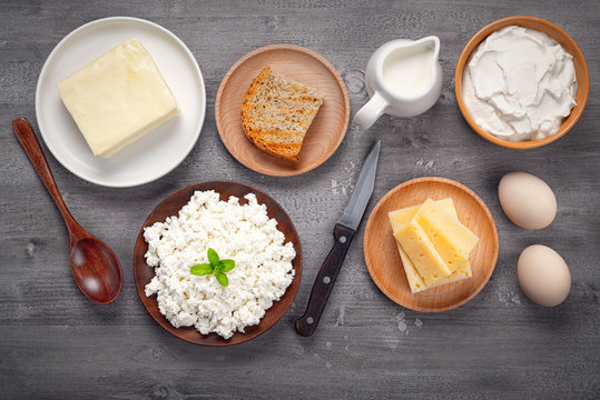 Different types of dairy products, bread and eggs on a wooden table