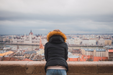 Young woman in the fishermen's bastion in Budapest, in the background the budapest parliament