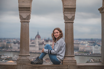 Fototapeta na wymiar Young woman in the fishermen's bastion in Budapest, in the background the budapest parliament
