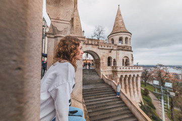 Obraz premium Young woman sitting in the Fisherman's Bastion overlooking the city of Budapest, Hungary