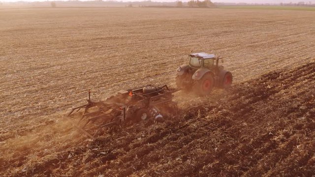 Agricultural tractor is working in the field. Cultivation of soil for sowing. Rural scene.