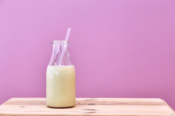 Closeup of a bottle of milk with a pink background.