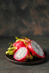 Plate with tasty dragon fruit on dark background