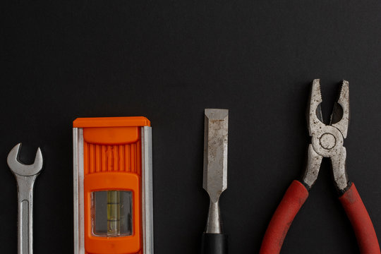 Pinzas, formon y niveleta  acomodados sobre un fondo de color negro