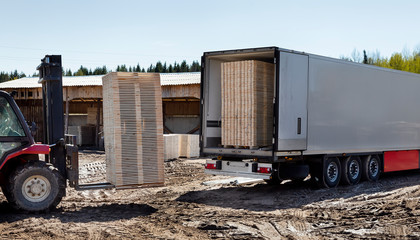 The machine loads the boards, lumber from the finished goods warehouse onto the truck