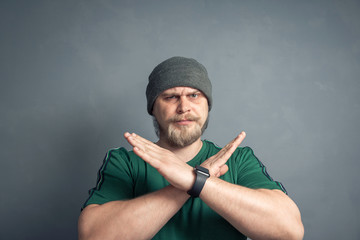 An irritated bearded man crosses his arms in the x sign and looks displeased, which means stop,...