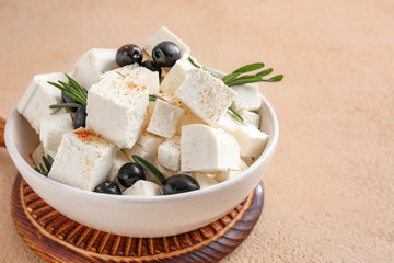 Bowl with tasty cut feta cheese and olives on color background