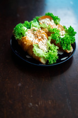 Chicken salad in croissant bun with a healthy salad leaves and tomatoes on a dark, wooden background.