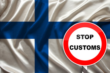 customs sign, stop, attention against the background of the silk national flag of Finland, the concept of border and customs control, violation of the state border, tourism restrictions