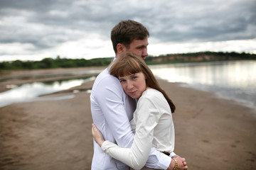 Fototapeta premium beautiful couple embraces on the beach. The concept of hugs and breakups. Feelings and emotions. Portrait of a woman and a man in close-up.