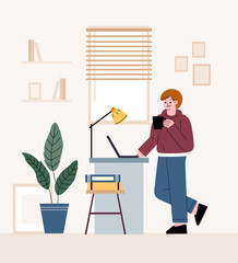 Man freelancer. Standing in front of a table and working on a laptop. Telecommuting at home.