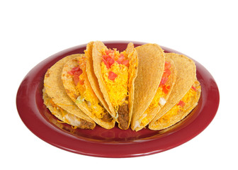Five crispy tacos on a red plate isolated on white. Popular Americanized Mexican food. Viewed from above at an angle.