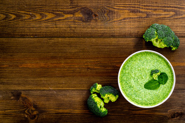 Green vegetable cream soup - broccoli - on wooden kitchen table top view copy space