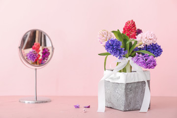 Box with beautiful hyacinth flowers on table against color background