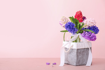 Box with beautiful hyacinth flowers on table against color background