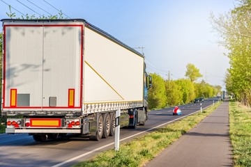 Truck overtakes a small car . Truck moves on the road at speed, delivery of goods .Transport in Europe
