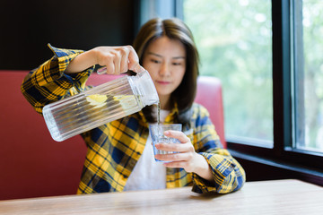 Young Asian woman pouring water into glass.