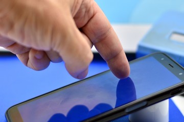 dedo sobre la pantalla de  un teléfono móvil con fondo difuminado