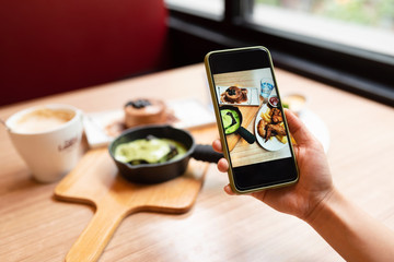 Woman's hand was taking photo of her food with smart phone.
