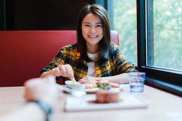 Young Asian woman enjoying delicious food with her friend.
