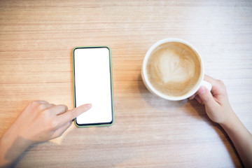 Cropped hands of woman's hand using smart phone on wooden table.