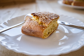 Close up view on cornbread corn pone in a white plate on the wooden table covered with sesame seed organic vegetarian food vegan with fork and knife beside side view