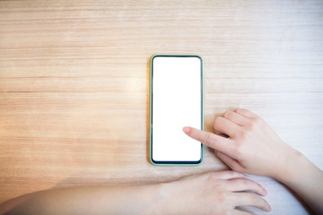 Cropped hands of woman's hand using smart phone on wooden table.