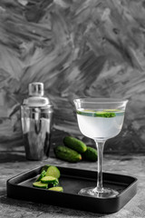 Glass of tasty cucumber martini and shaker on table