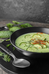 Bowl with cold cucumber soup on table, closeup