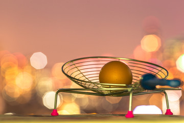 A blurry abstract background of bokeh lights falling onto a hen's egg with a small frying basket placed on a wooden floor.