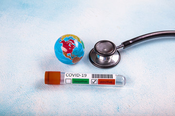 Coronavirus updates text with stethoscope, world globe and blood sample vacuum tube on blue...