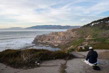 Fototapeta premium Man is praying on cliff at sunset ocean, San Francisco, California
