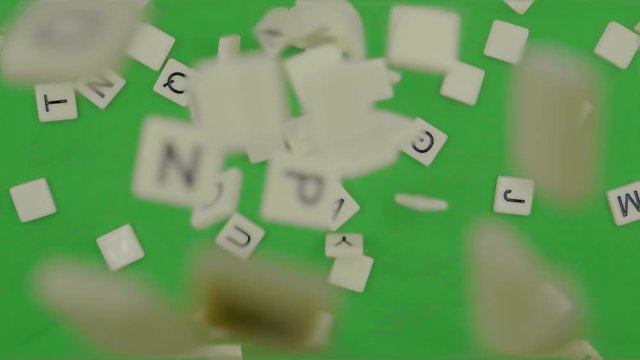 Random Alphabet Scrabbles falling down to green background . alphabet dropping on green table