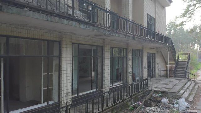 Abandoned building exterior with broken windows. Aerial side view. Low angle shot