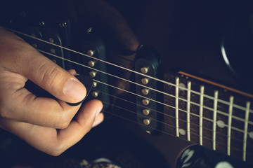 Guitarist is rehearsing playing black vintage electric guitars. Closeup  girl's hand is holding the...