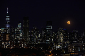 Fototapeta premium Księżyc w pełni i nocne niebo nad panoramą miasta.