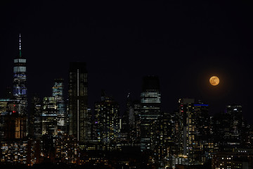 Fototapeta na wymiar A full moon and night sky over a downtown city skyline.
