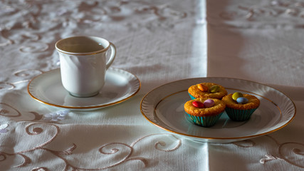Three cupcakes on a table with a elegant cup