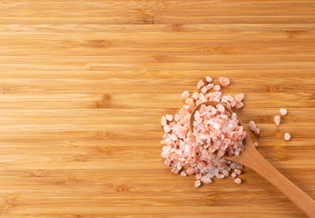 Obraz na płótnie Canvas Wooden spoon with pink rock salt placed on wooden background