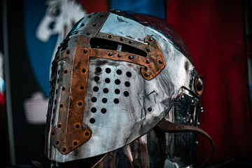 Shiny silver medieval iron knight helmet with a golden cross, full of scratches due to battles