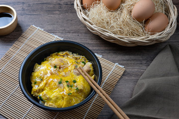 Oyako-don rice bowl topped with chicken, onions and egg cooked with special sauce. oyakodonburi Japanese food on wooden background.