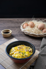 Oyako-don rice bowl topped with chicken, onions and egg cooked with special sauce. oyakodonburi Japanese food on wooden background.