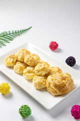 Delicious eclairs or cream puff or French profiteroles or choux dough filled with vanilla custard cream,on the white plate. 