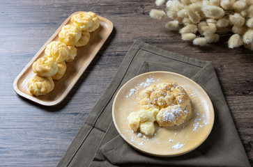 Delicious eclairs or cream puff or French profiteroles or choux dough filled with vanilla custard cream,on wooden background.