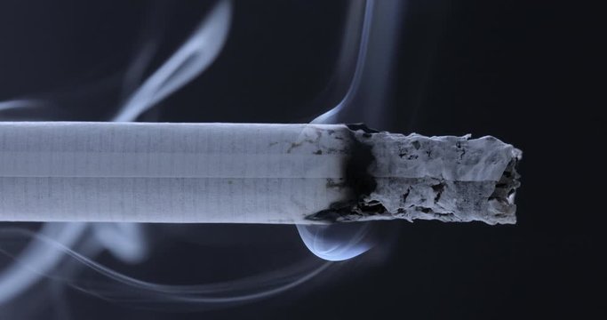 Smoldering cigarette on a black background. Smoke from a cigarette	