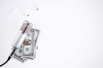 Concept of earning money by Podcast.  Earphones, a microphone and some money on white background.